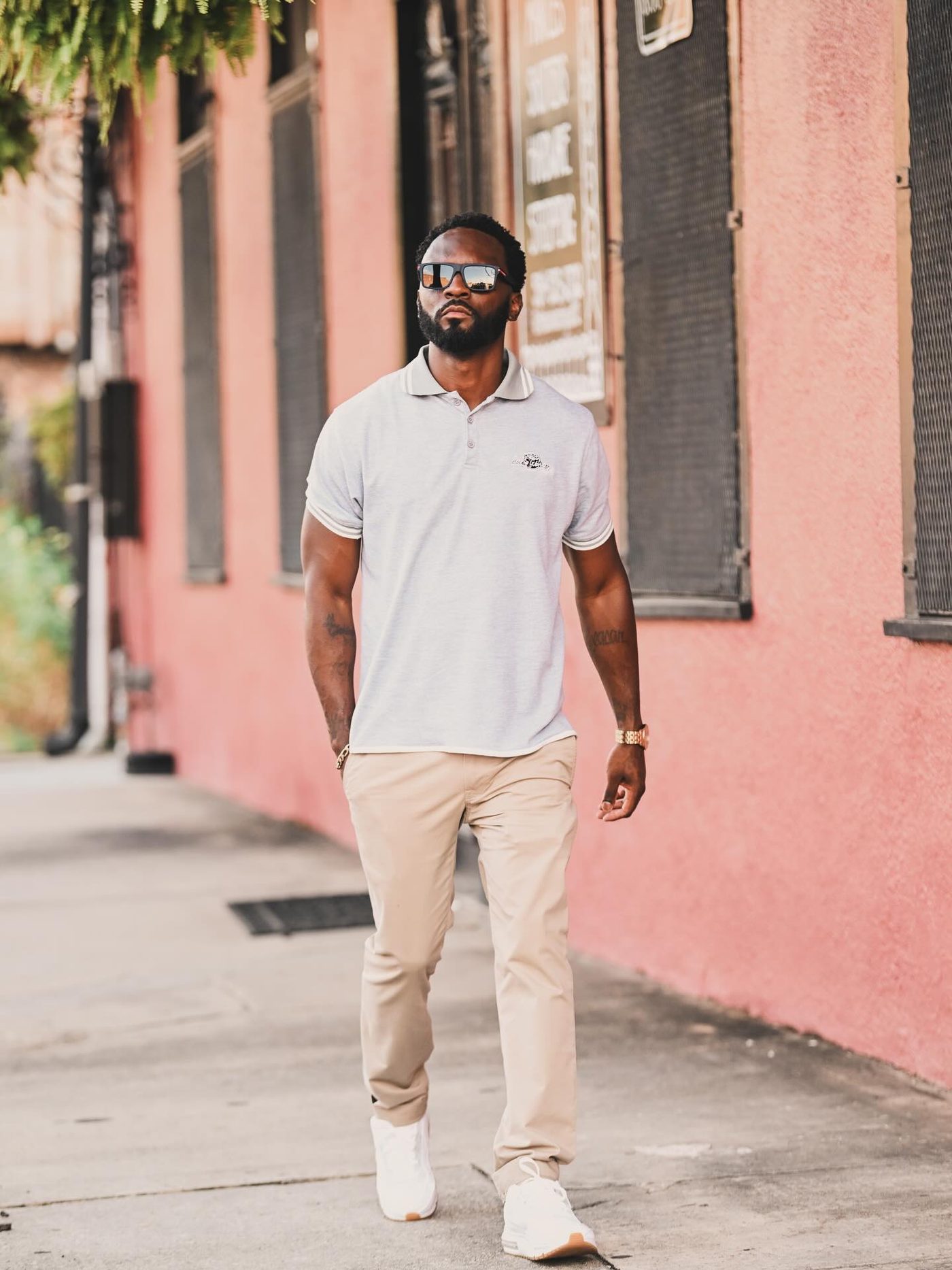 Grey Lone Wolves polo worn against a pink building